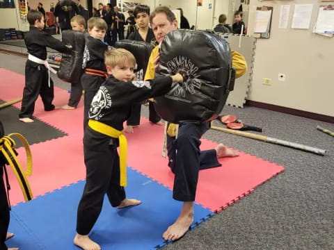 a person and a boy in a karate uniform in a room with other people
