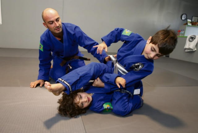 a person holding a boy in a karate uniform