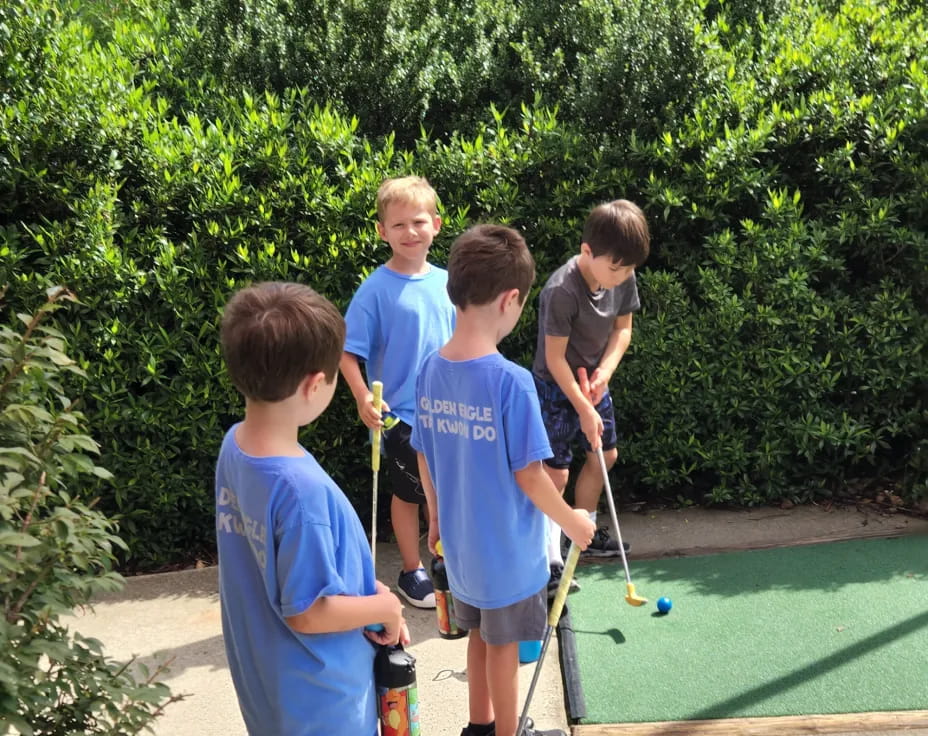a group of boys playing mini golf