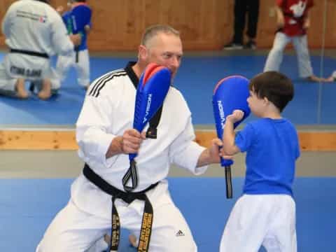 a person in a karate uniform with a boy in a blue shirt