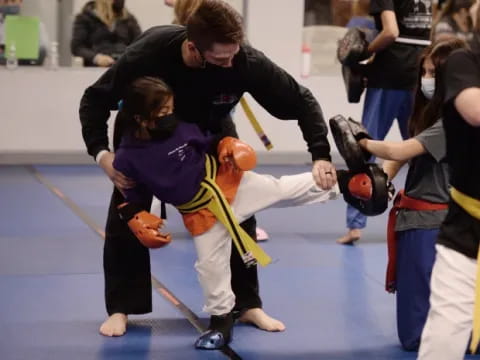 a person helping a child do a martial arts move