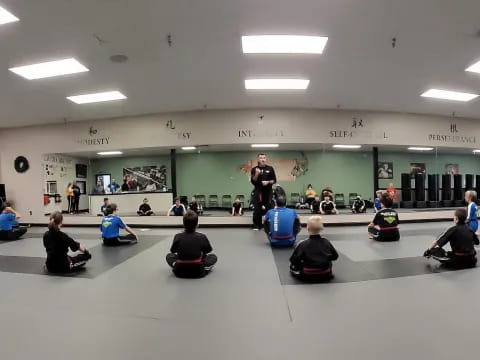 a group of people sitting on the floor in a room with a person standing on a bike