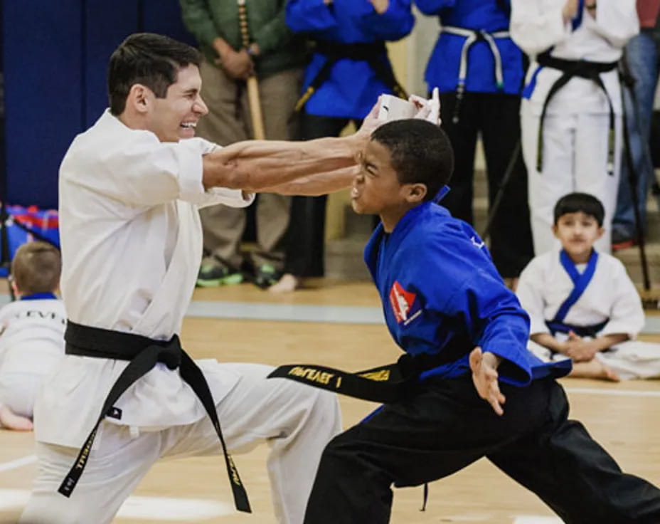 a person in a karate uniform kicking another man in the face