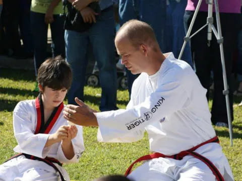a person and a boy in karate uniforms sitting on the ground