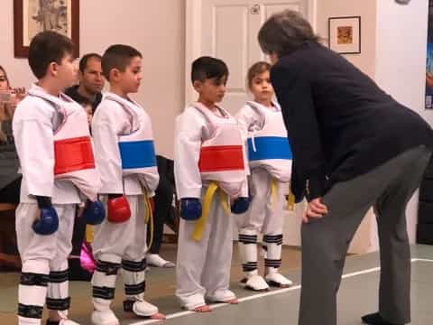 a person standing in front of a group of kids in karate uniforms