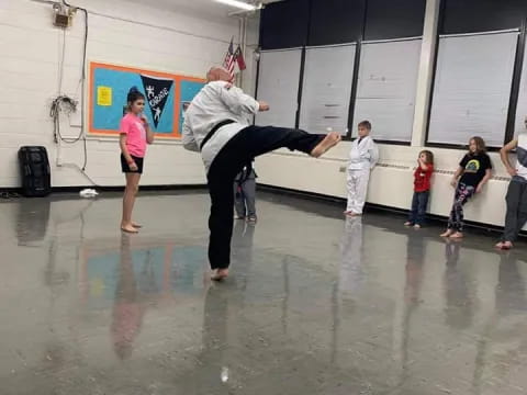 a man doing a handstand on a large floor in a room with other people
