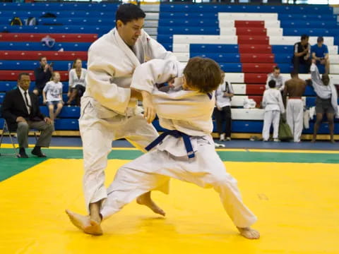 a man and a boy in karate uniforms on a yellow mat