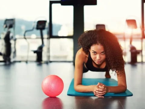 a woman sitting on the floor with a ball in front of her