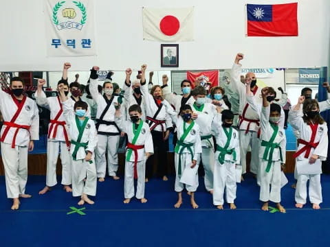 a group of people in white karate uniforms holding up their hands