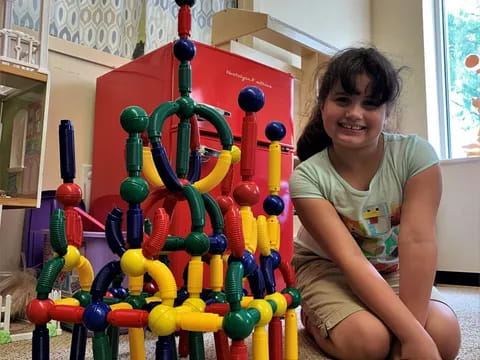 a girl sitting on the floor next to a colorful toy