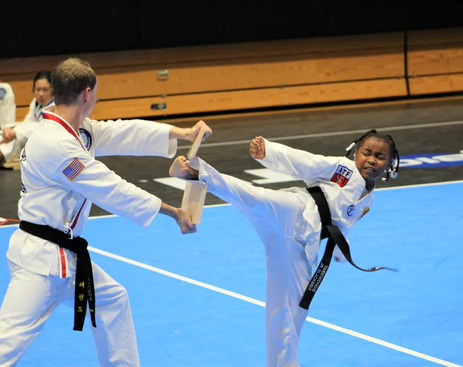 a man and a woman in karate uniforms with their hands up