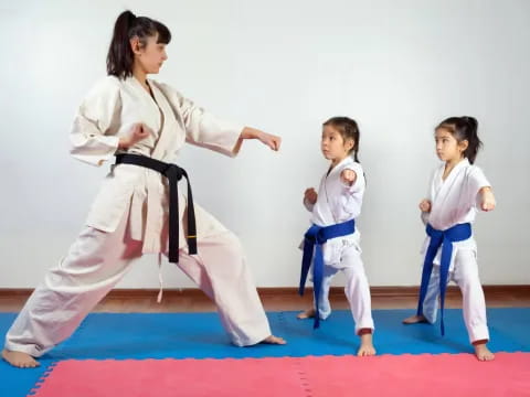 a person and two children in karate uniforms