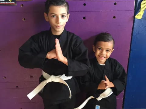 a couple of boys in black karate uniforms holding white paper