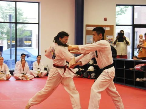 a man and a woman in karate uniforms in a room with other people