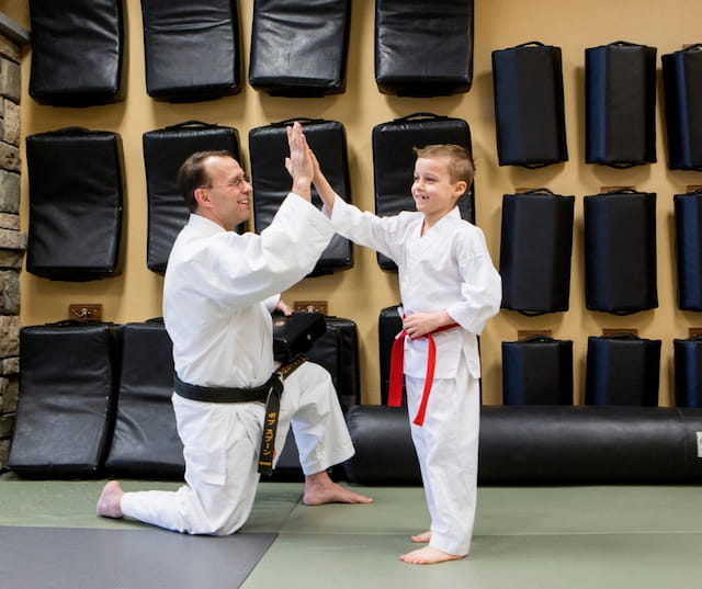 a person and a boy in karate uniforms with their hands up