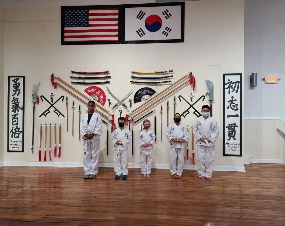 a group of people in white uniforms holding swords in a room with flags