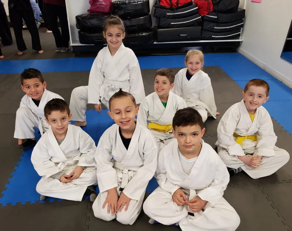 a group of boys in white karate uniforms sitting on the floor