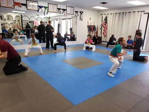 a group of people sitting on mats in a room with a flag