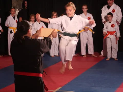 a man in a karate uniform kicking a girl in the air