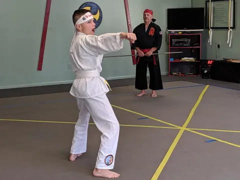 a boy in a karate uniform holding a sword