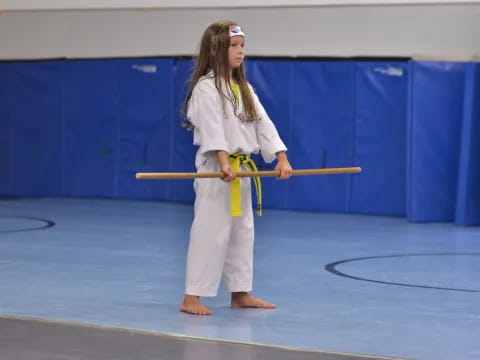 a person in a karate uniform holding a yellow stick
