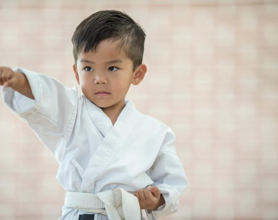 a young boy holding a white belt