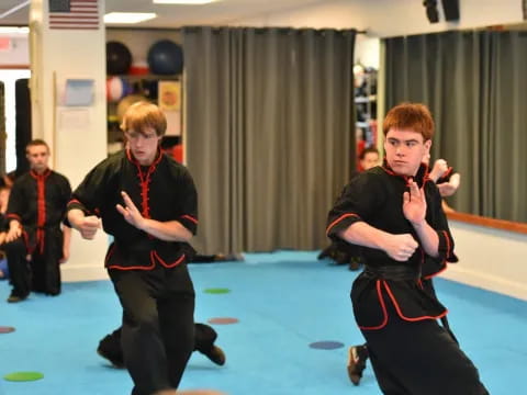 a group of boys in black karate uniforms with red belts on their hands