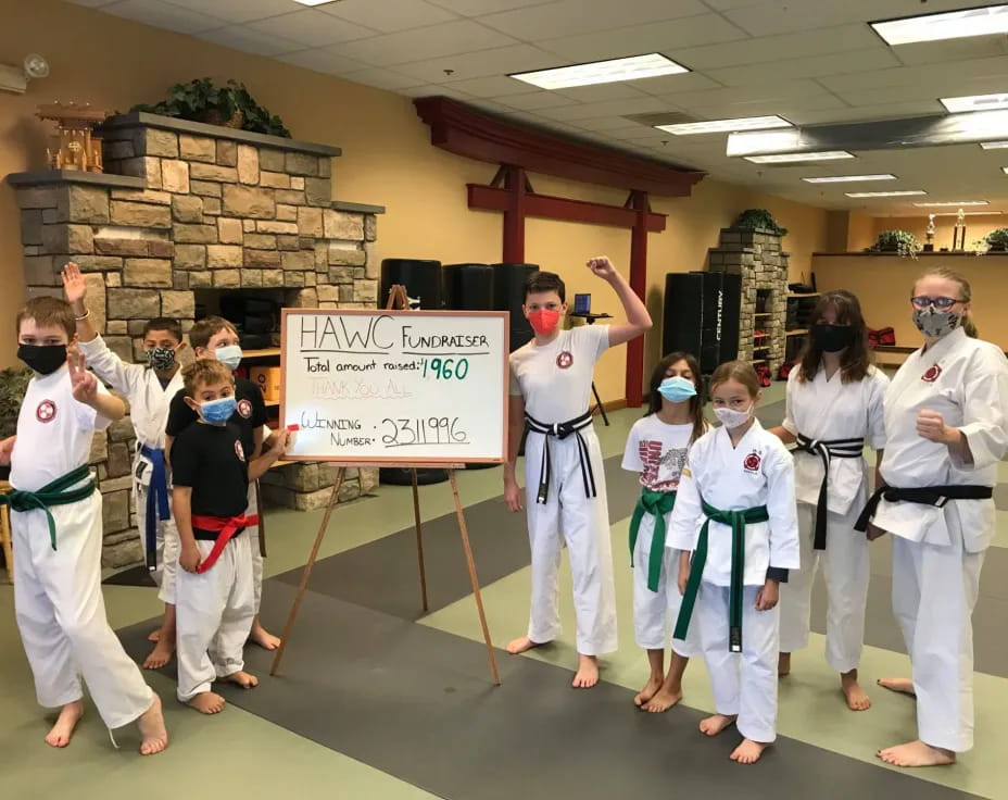 a group of people in karate uniforms holding a sign