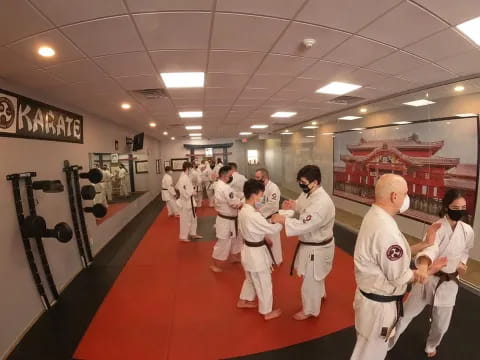 a group of people in white karate uniforms in a room with red carpet