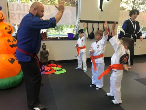 a man standing in front of a group of kids in karate uniforms