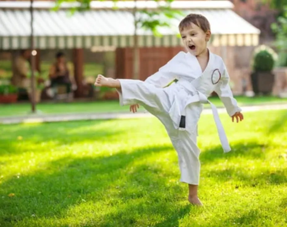 a boy in a karate uniform jumping in the air