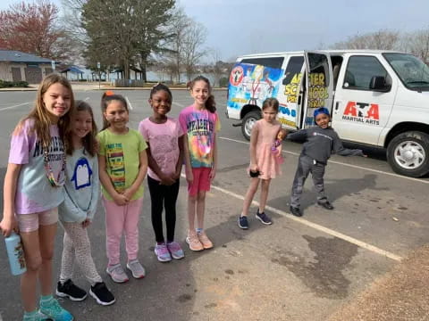 a group of people posing for a photo in front of a van