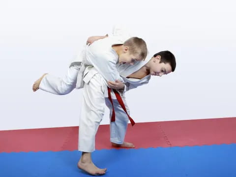 a man and a boy in karate uniforms on a red mat