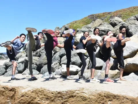 a group of people posing for a photo on a rocky beach