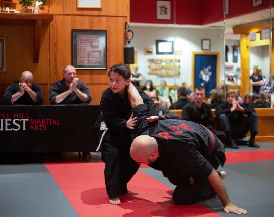 a person kicking another man in the face with a crowd watching