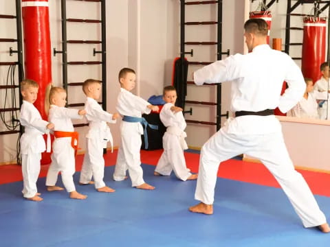 a man in white karate uniform with a group of boys in white karate uniforms