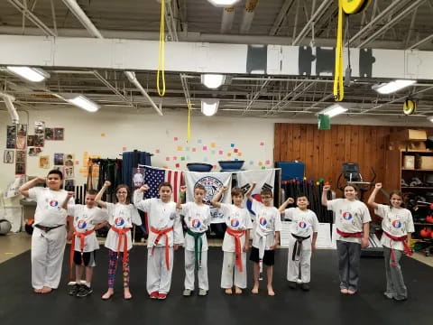 a group of people in white karate uniforms in a room with a flag