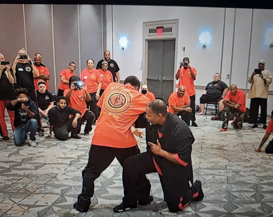 a person kicking another man in the face with a crowd watching