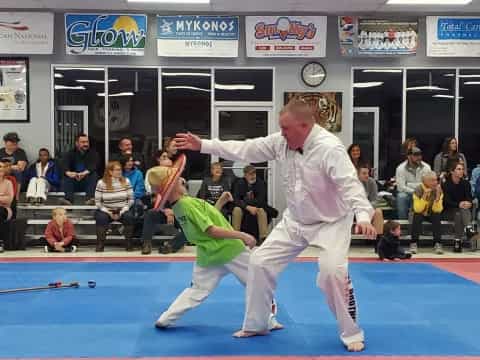 a person in a karate uniform kicking another man in a karate uniform