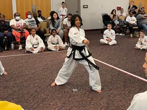 a person in a karate uniform with a rope in front of a group of people