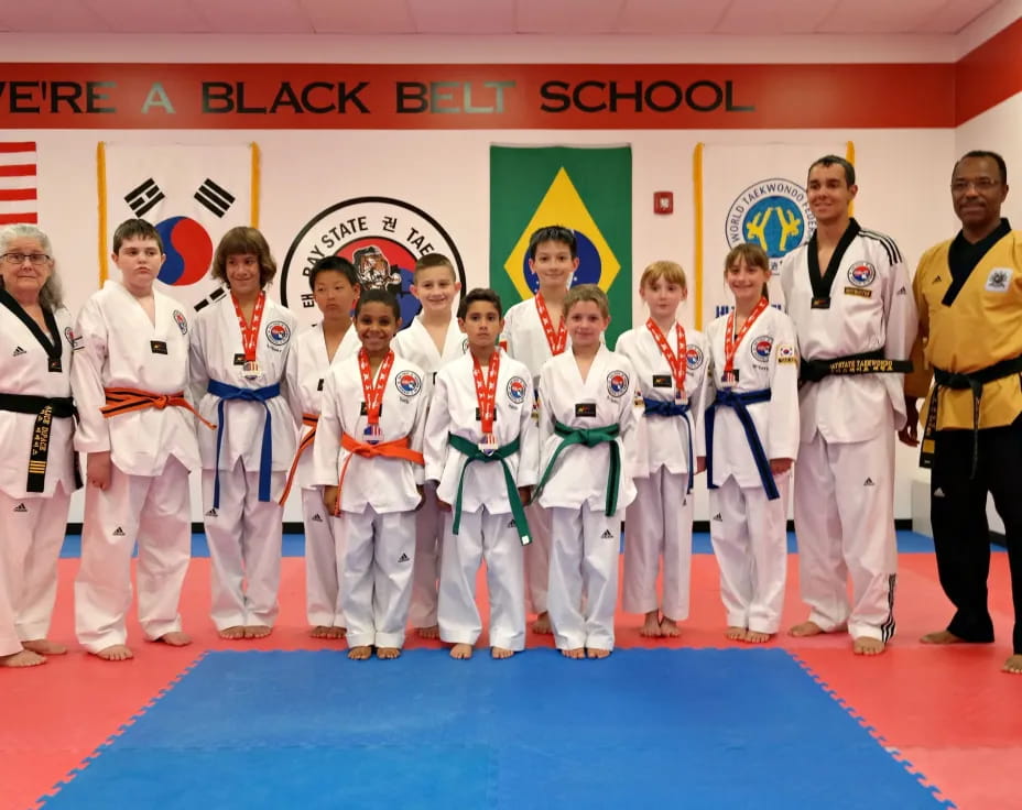 a group of people in white karate uniforms standing on a blue mat