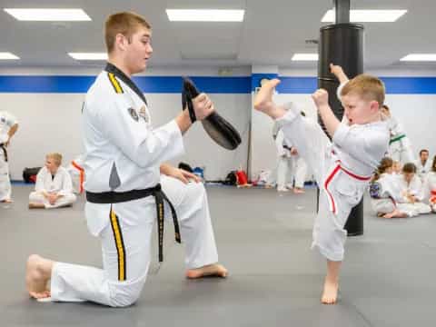 a person and a boy in karate uniforms with their hands up