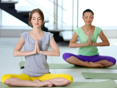 a couple of women sitting on yoga mats