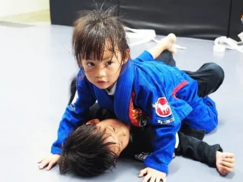 a child lying on the floor with another child lying on the ground