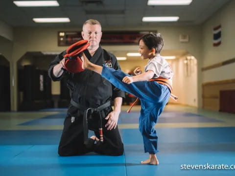 a person and a boy in a karate uniform with a red belt