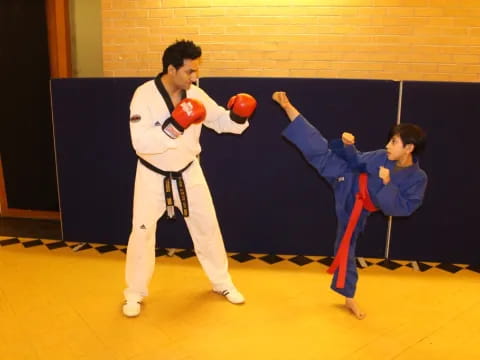 a man in a karate uniform kicking a boy in a blue uniform
