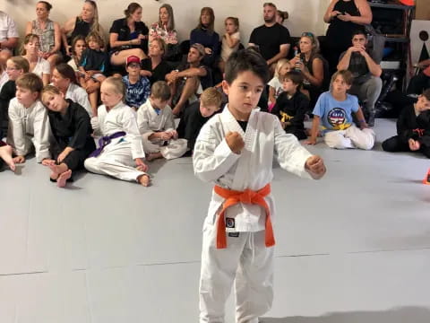 a boy in karate uniform in front of a crowd of people