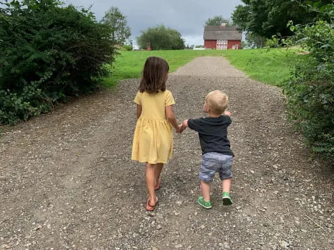 a couple children walking on a gravel road