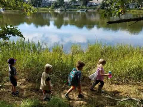 a group of children walking by a lake