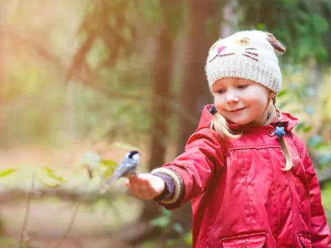 a little girl holding a bird